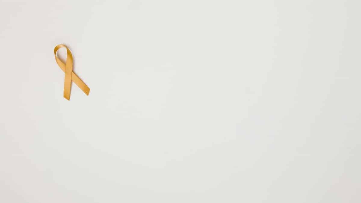 Gold ribbon on white background symbolizing childhood cancer awareness.