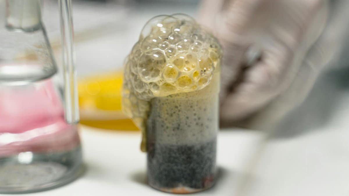 Close-up of a bubbling chemical reaction in a lab setting, showcasing frothy bubbles.