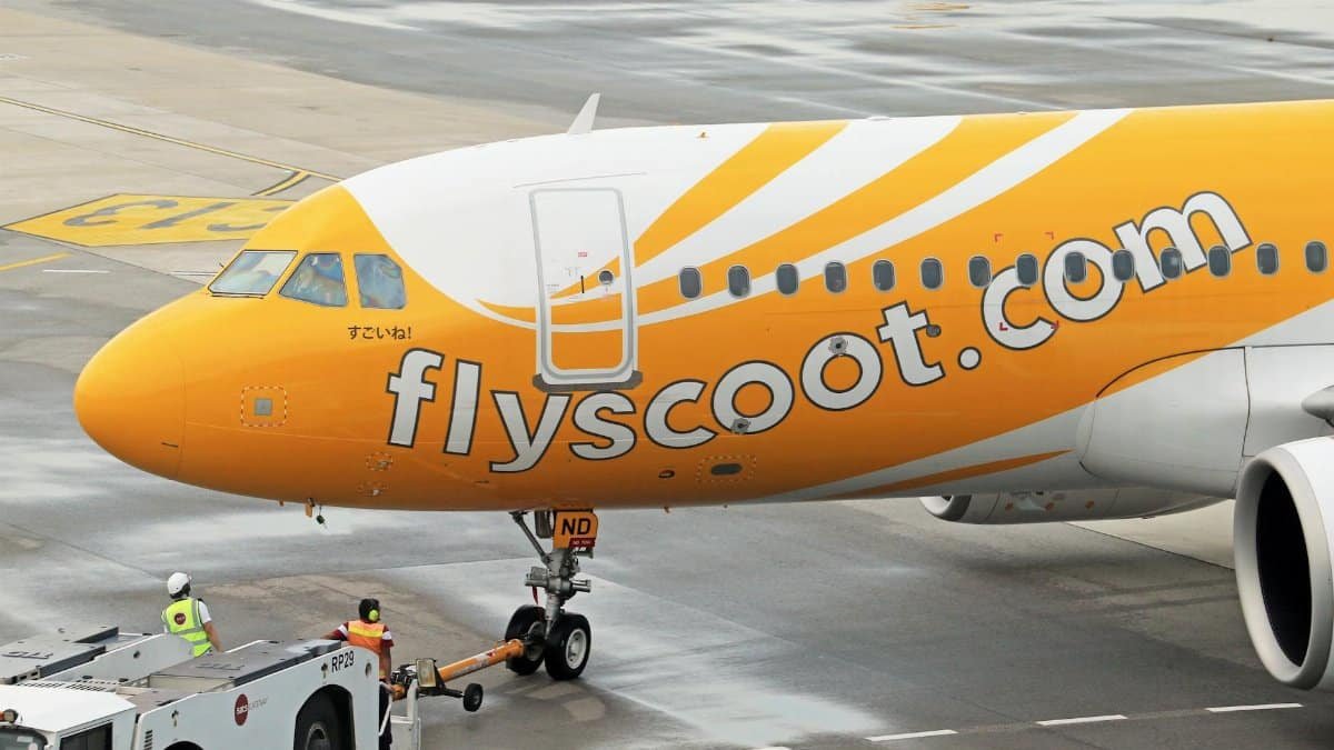 Scoot Airbus A320 being towed by a pushback tug at an airport apron.