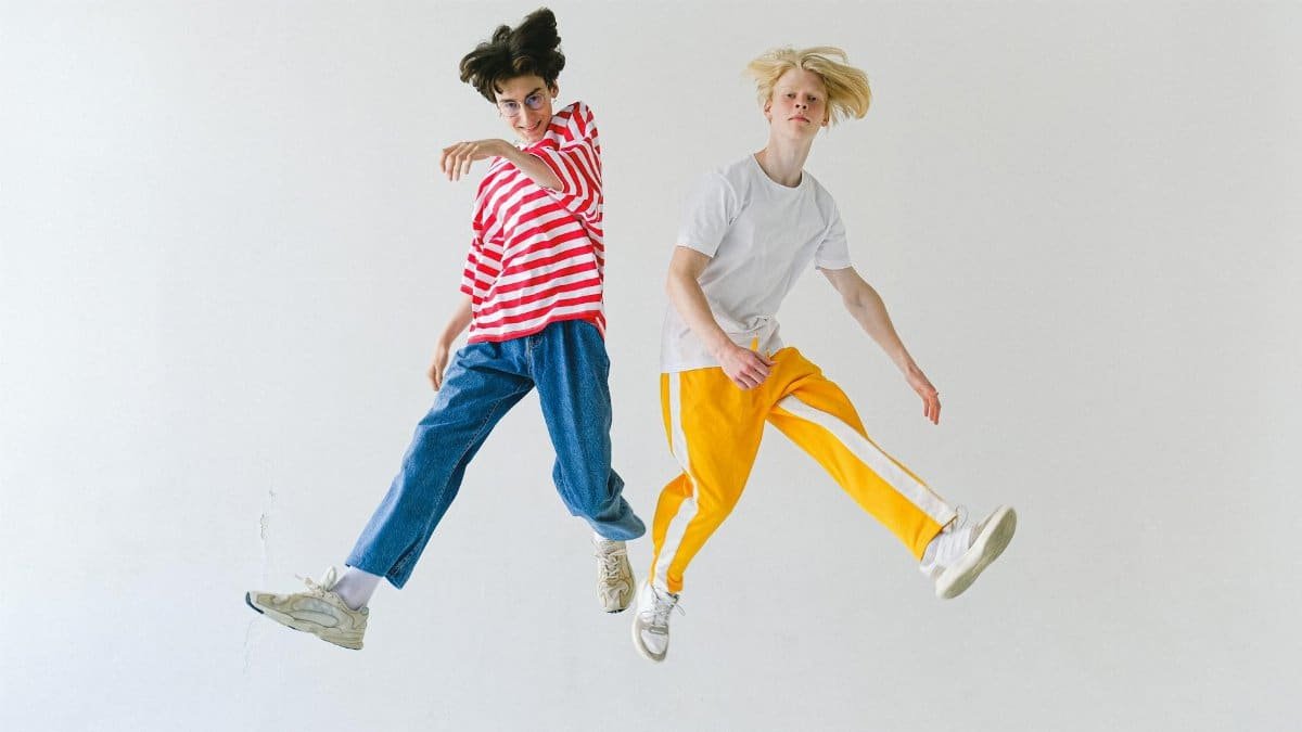 Two teenagers jumping energetically in a studio setting, expressing freedom and joy.