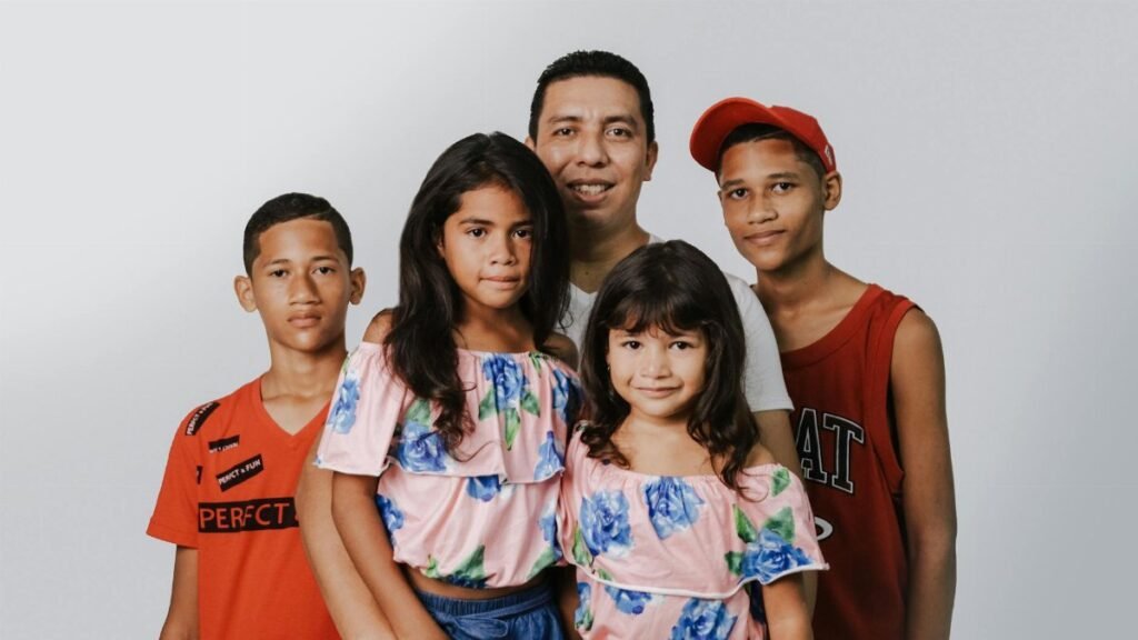 A joyful family portrait featuring a father and four children against a white background.