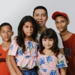 A joyful family portrait featuring a father and four children against a white background.