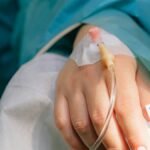 Close-up of a patient's hand with intravenous therapy and pulse oximeter, symbolizing healthcare and treatment.