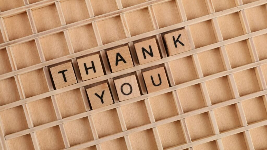 Wooden letter tiles spelling 'thank you' on a grid background, perfect for gratitude themes.