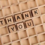 Wooden letter tiles spelling 'thank you' on a grid background, perfect for gratitude themes.