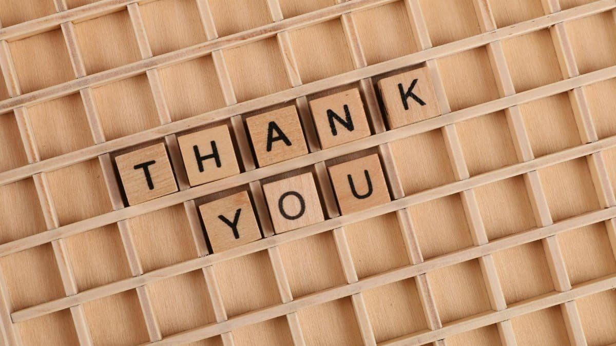 Wooden letter tiles spelling 'thank you' on a grid background, perfect for gratitude themes.