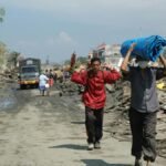 People walking through debris in Banda Aceh after a natural disaster, reflecting resilience.
