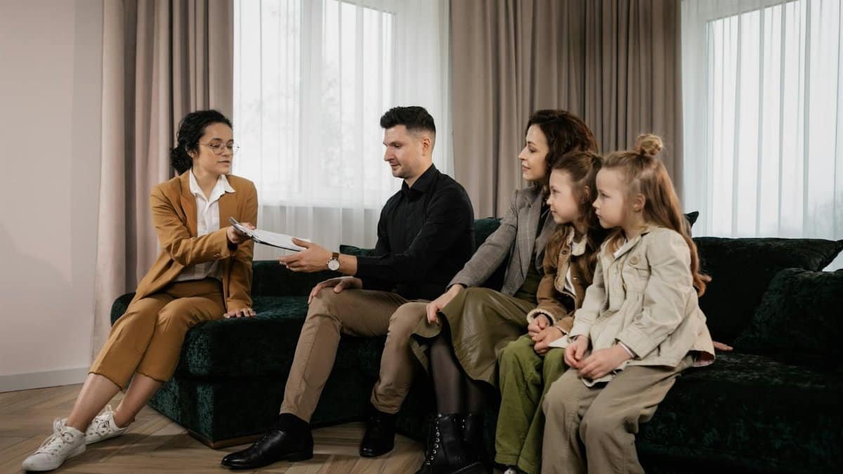 A family meets with a real estate agent in a stylish living room, reviewing documents for a potential home purchase.