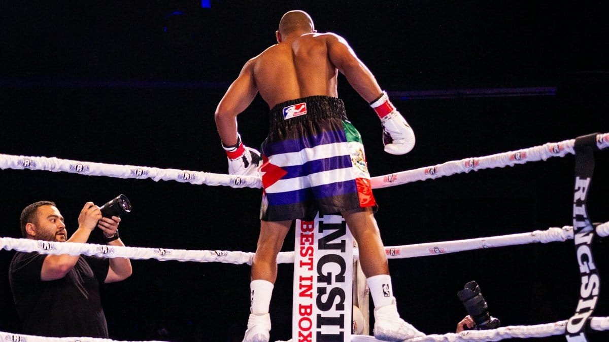 Boxer celebrates victory in the ring, captured with photographers in action.