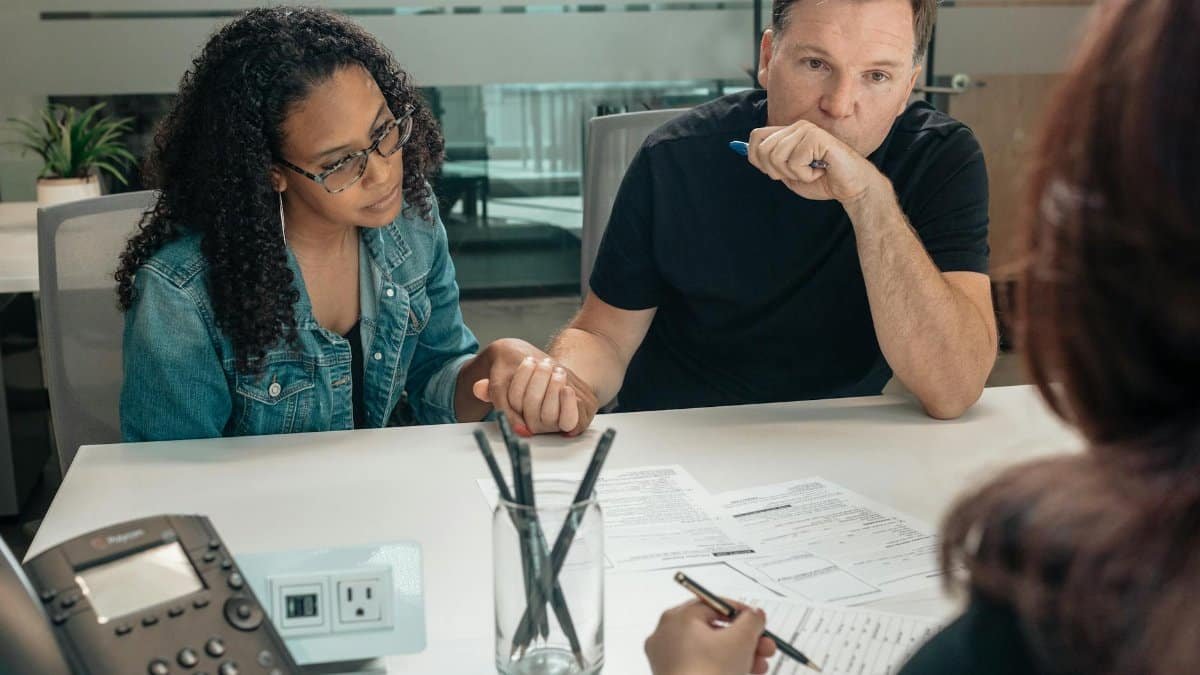 A couple discusses adoption process with an advisor in a modern office setting.