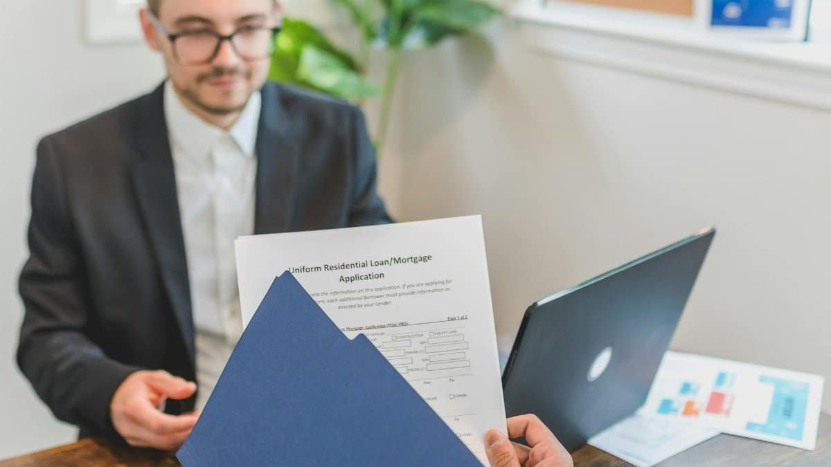 Mortgage broker and client discussing loan application with documents on table.