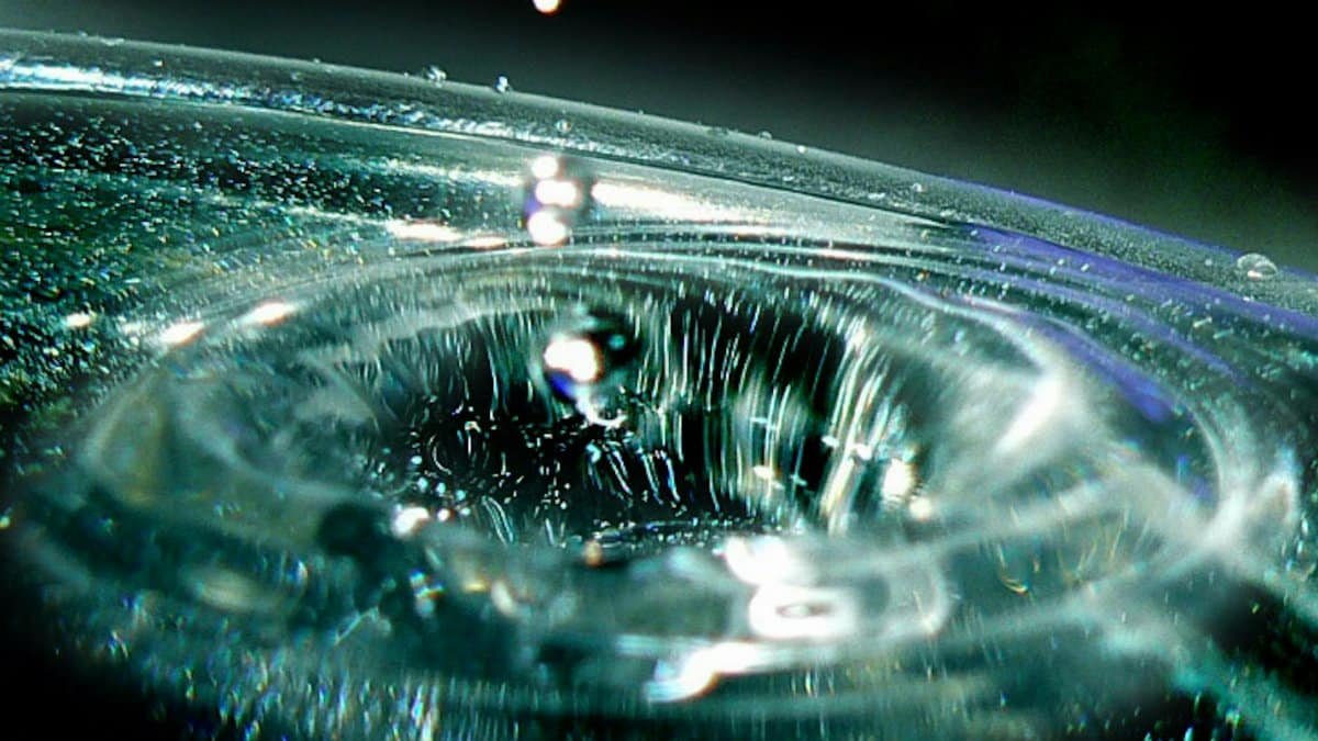 Close-up view of a water droplet creating ripples in a pool of water, capturing the moment of impact.