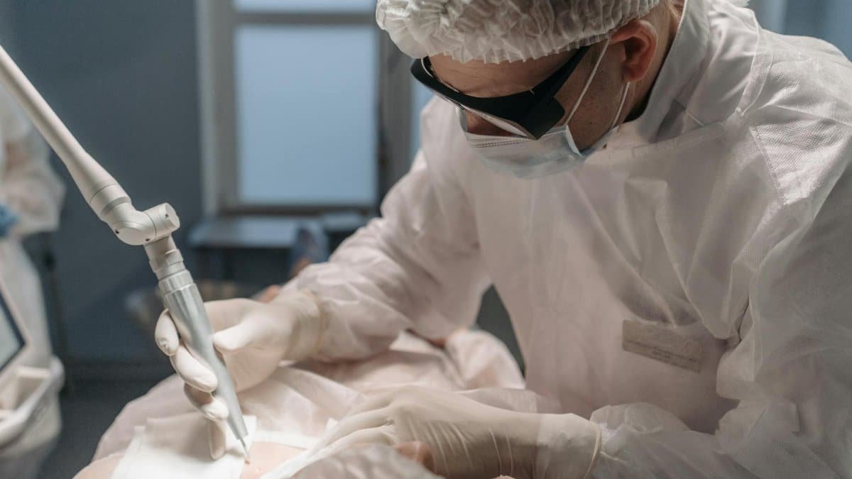 A focused surgeon performs laser surgery in a sterile operating room, emphasizing precision and care.