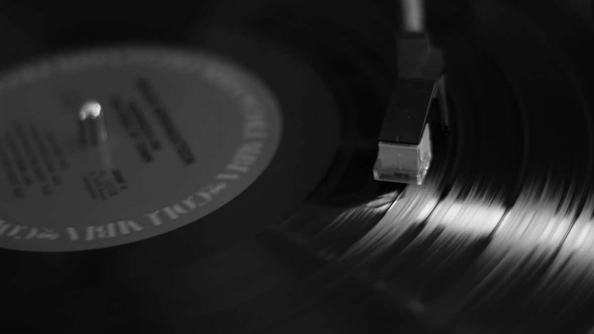 Artistic black and white close-up of a vinyl record on a turntable, emphasizing music nostalgia.