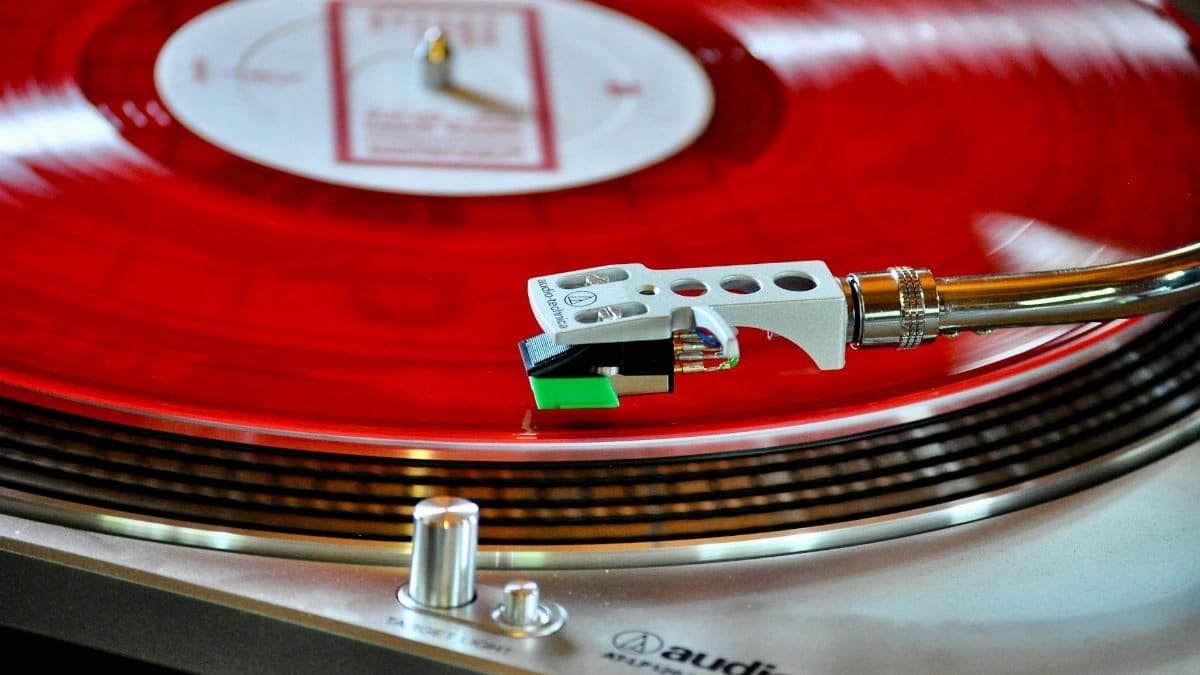 A detailed shot of a classic turntable playing a vibrant red vinyl record, showcasing a retro vibe.