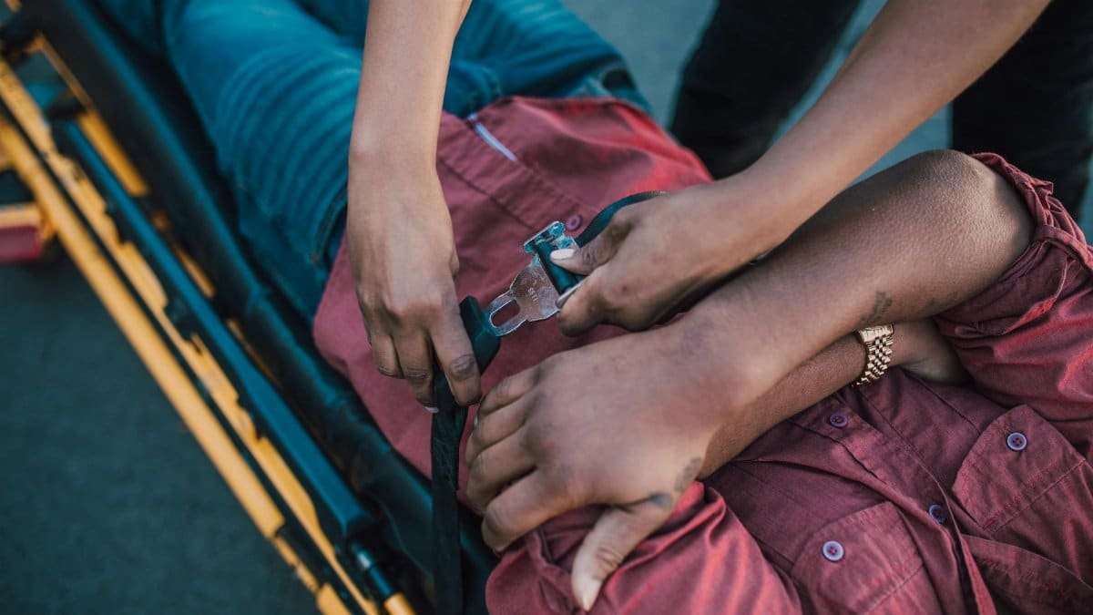 Close-up of a person securing an injured individual on a stretcher, providing emergency care.