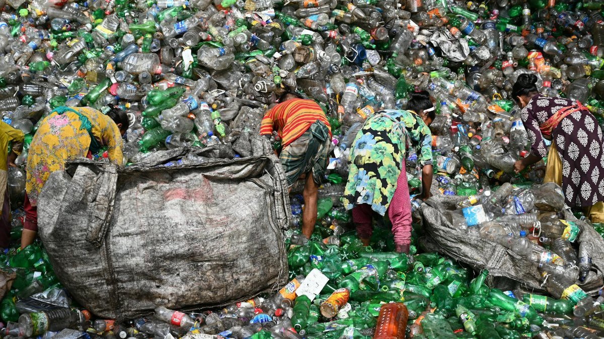 Workers sorting plastic waste at a landfill in Chattogram, Bangladesh. Environmental and recycling theme.