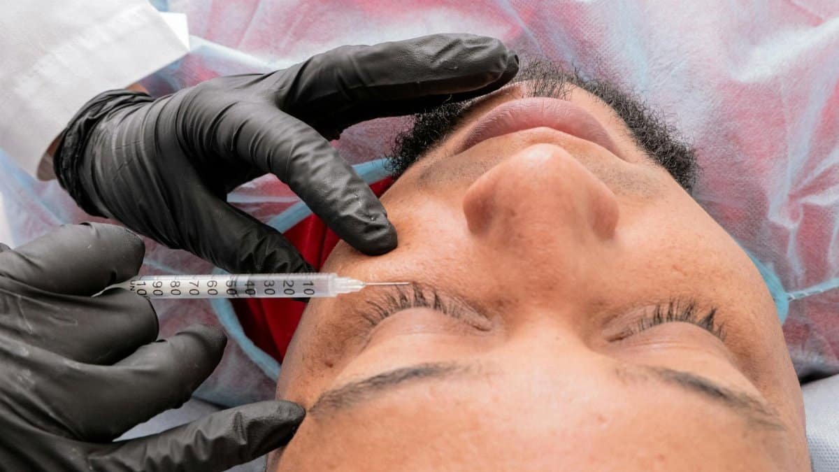 Man receiving facial treatment with syringe in medical facility.