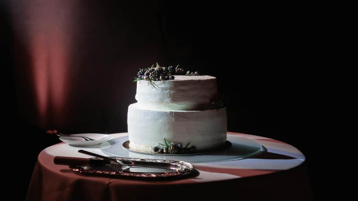 Classic two-tier wedding cake adorned with fresh berries, artfully lit.