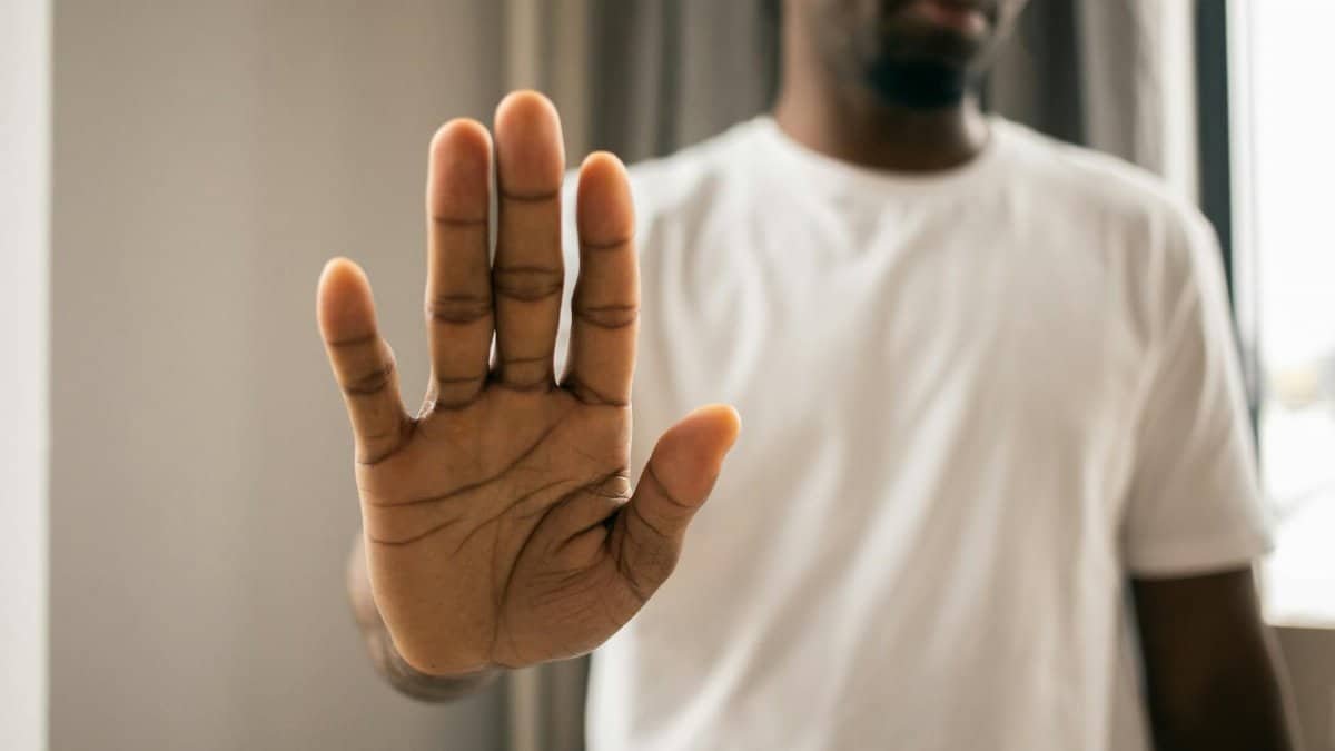 Close-up of a man with a hand gesture expressing stop or refusal indoors