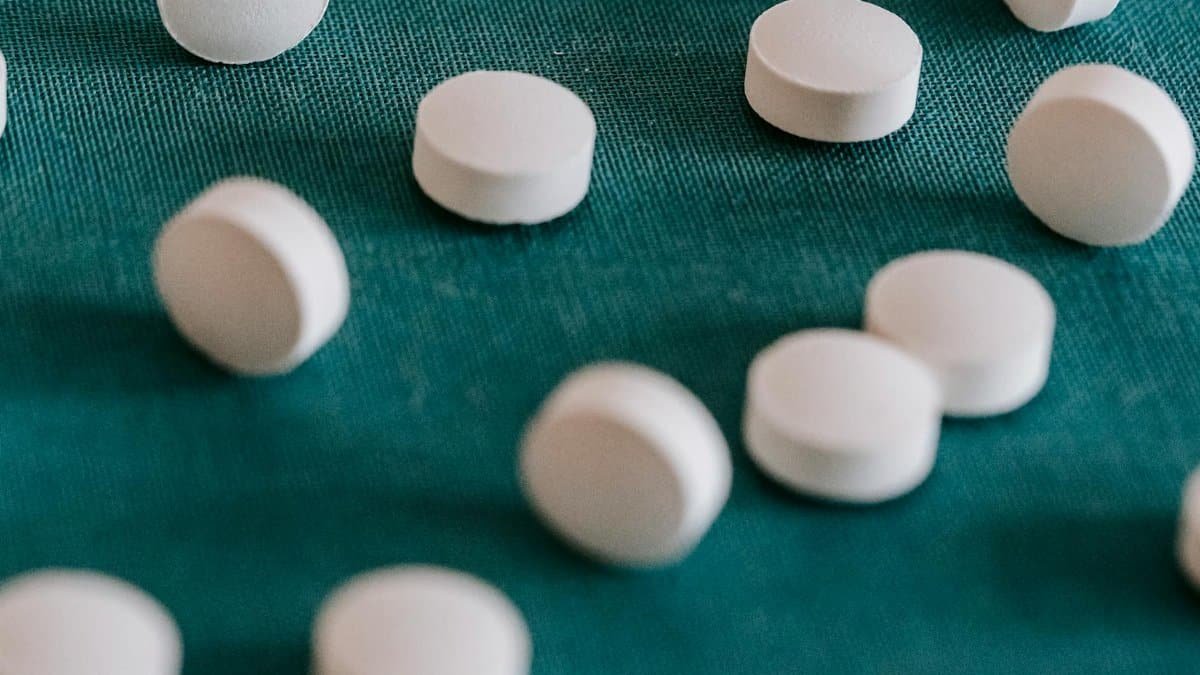 Closeup of similar round white pills spilled on green tissue in random order