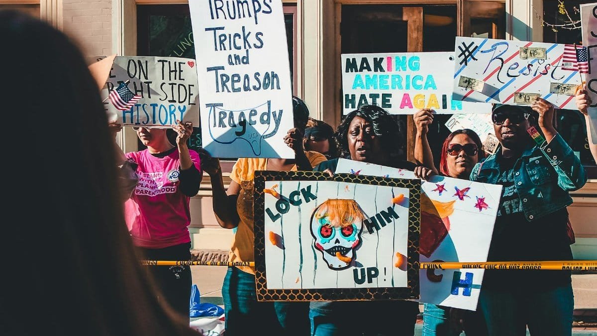 Protesters rally on Wheeling streets holding political signs and banners in a vibrant demonstration.