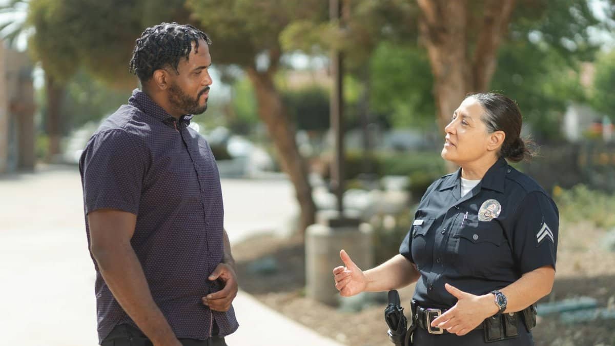 A police officer engaging warmly with a community member outdoors on a sunny day.