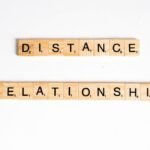 Conceptual image of Scrabble tiles spelling 'Distance Relationship' on a white background.