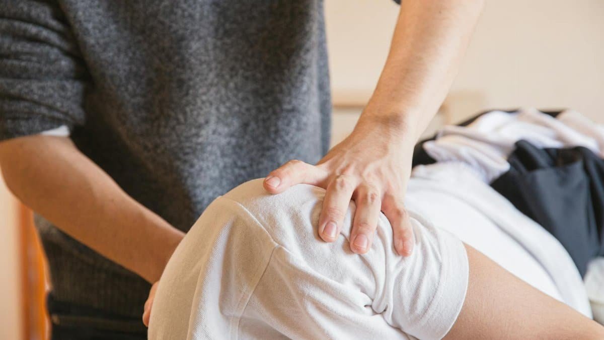 Close-up of a chiropractor performing shoulder therapy on a patient indoors.