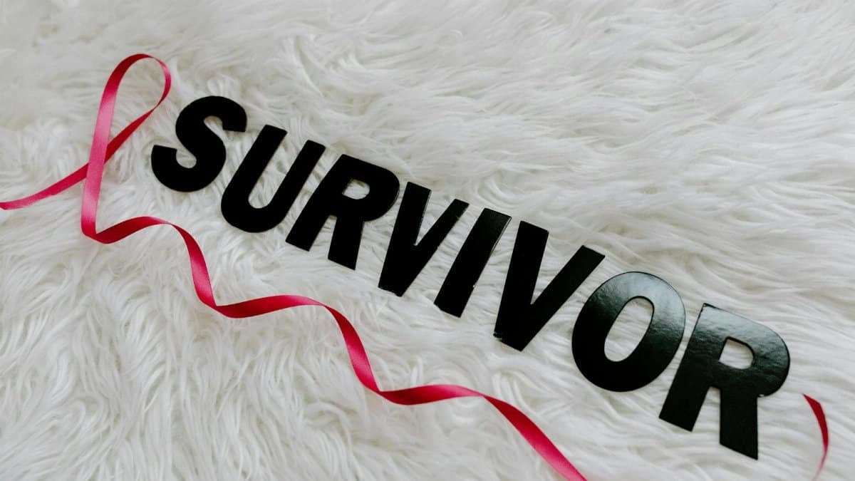 Pink ribbon with 'SURVIVOR' text symbolizing cancer awareness on white texture.