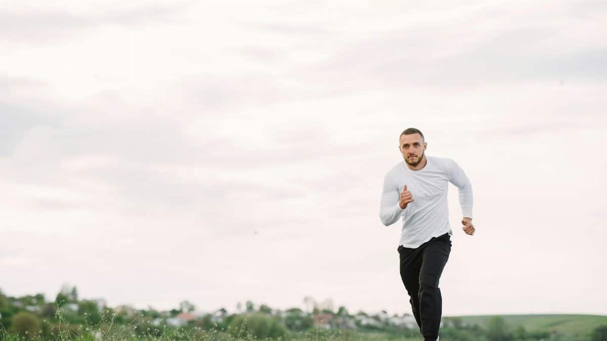 Adult man running on an empty road in casual sportswear, showcasing fitness and healthy lifestyle.