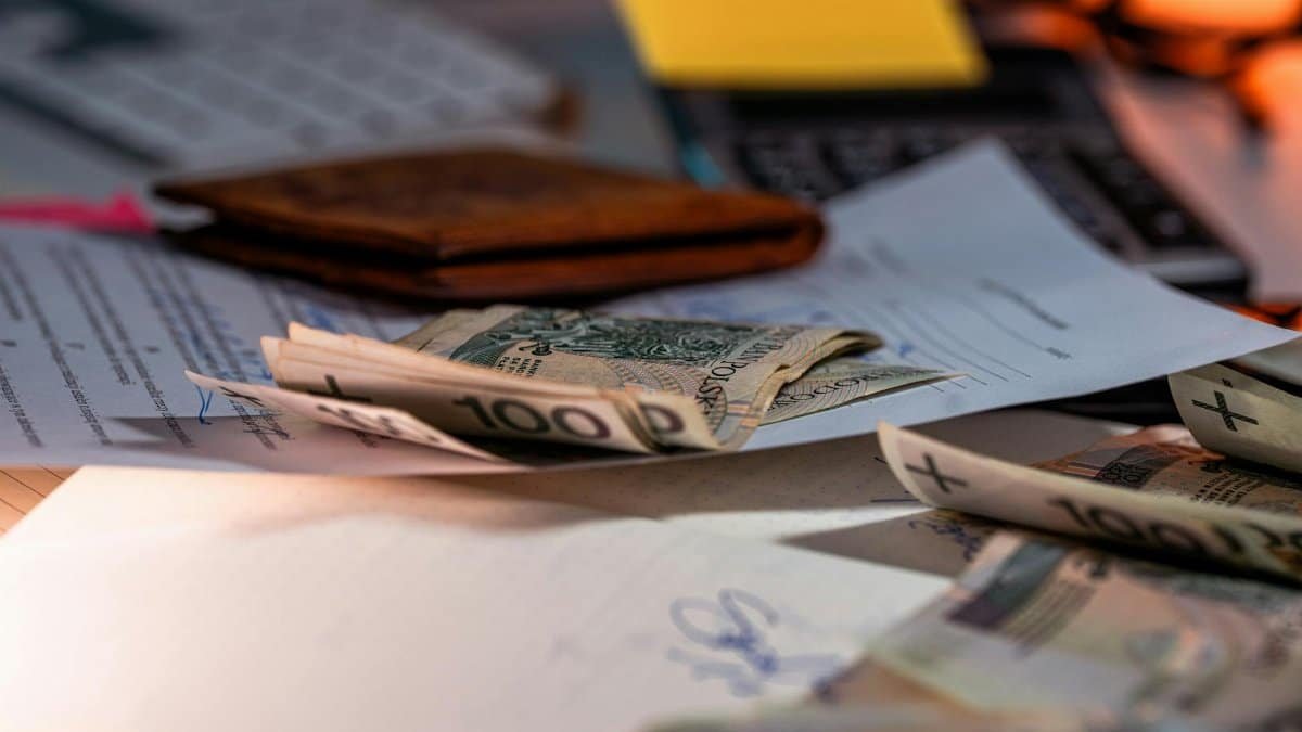 Zloty banknotes and financial paperwork scattered on a desk, representing budgeting and finance.