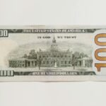 Detailed close-up of an American one hundred dollar bill on a neutral white background.