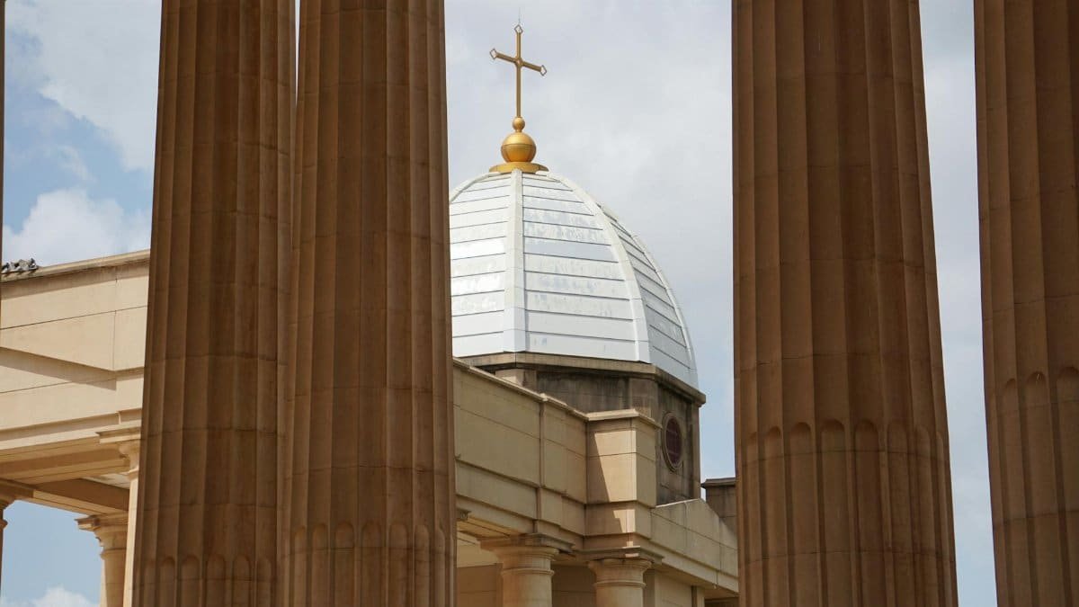Low angle view of the Basilica of Our Lady of Peace dome framed by columns in Yamoussoukro, Côte d'Ivoire.