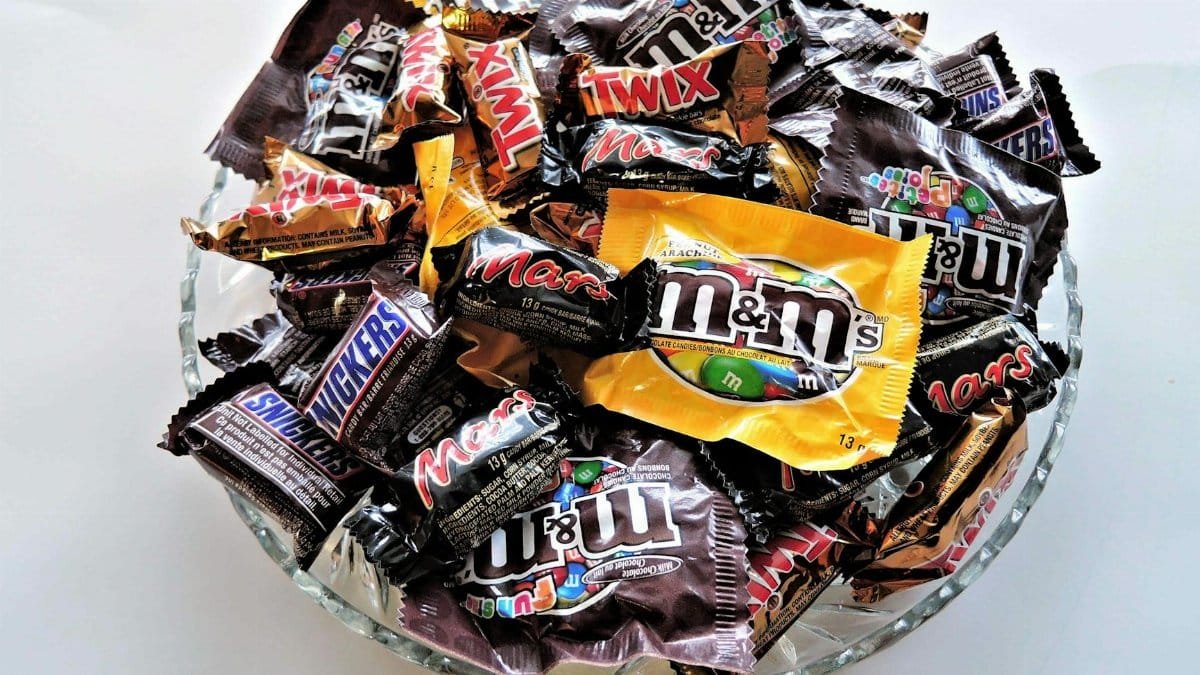 A bowl filled with various chocolate candies, including Twix, Snickers, and M&Ms, creating a vibrant dessert spread.