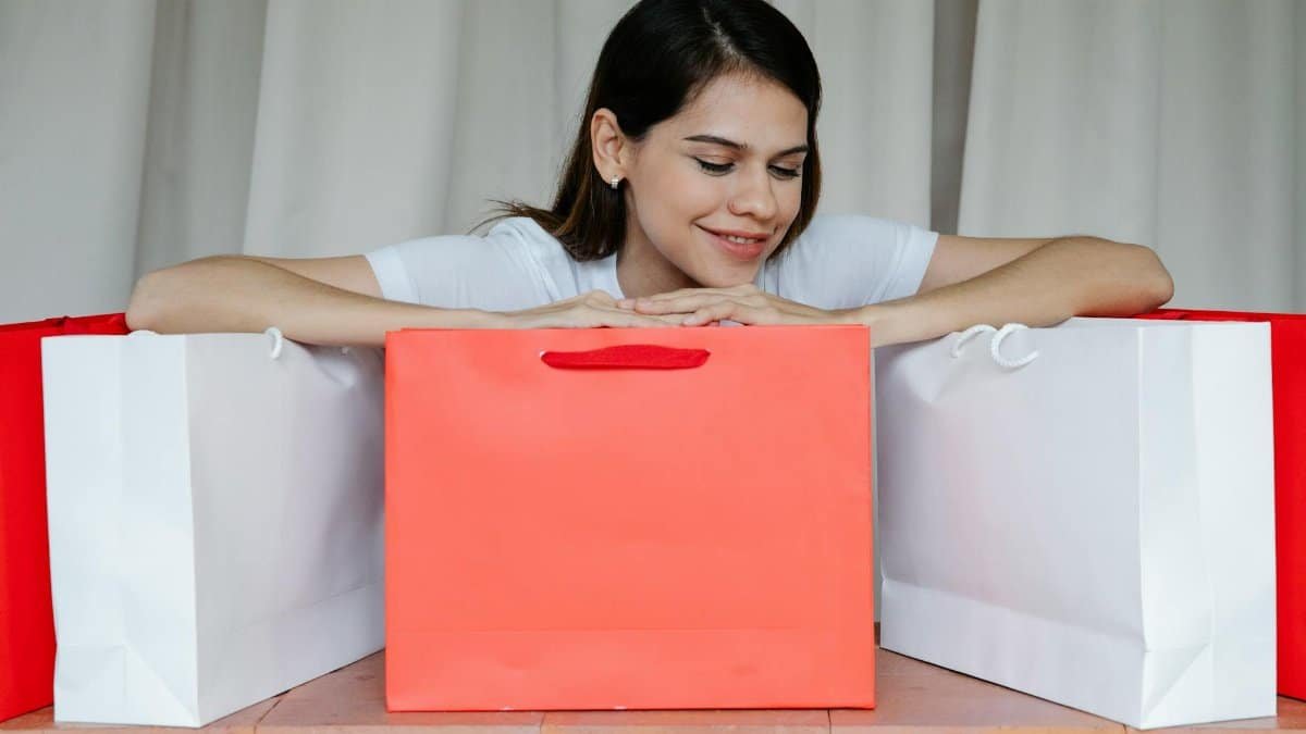 Happy woman surrounded by colorful shopping bags, showcasing retail therapy indoors.