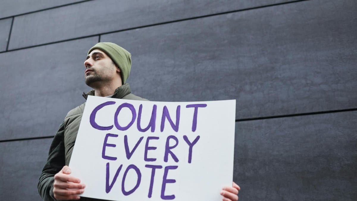 A man holding a 'Count Every Vote' placard, promoting democracy and voting rights.