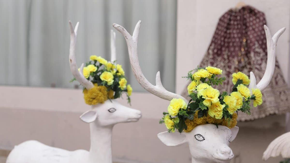Elegant Indian wedding decor with deer sculptures adorned with yellow flowers.