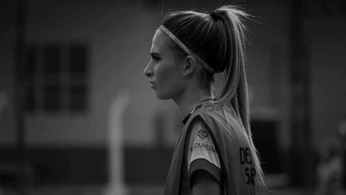 Black and white side profile of a female athlete wearing a sports jersey outdoors.