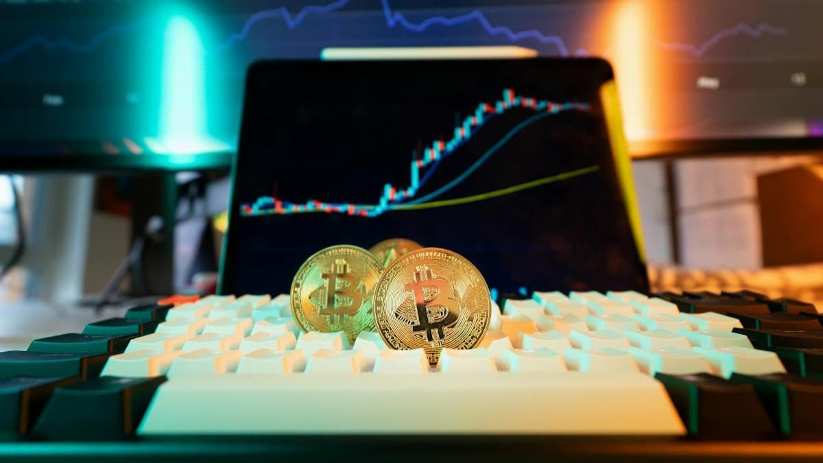 Close-up of Bitcoin coins on a keyboard with a trading chart in the background