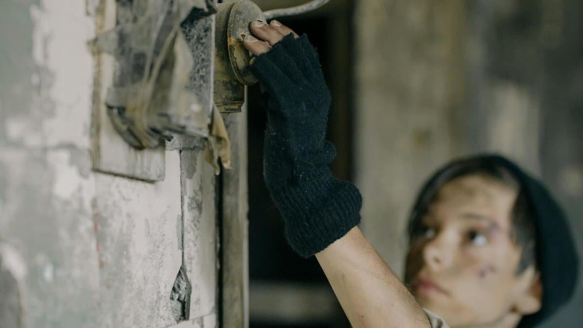 A child exploring a deteriorated building, touching an old light switch.