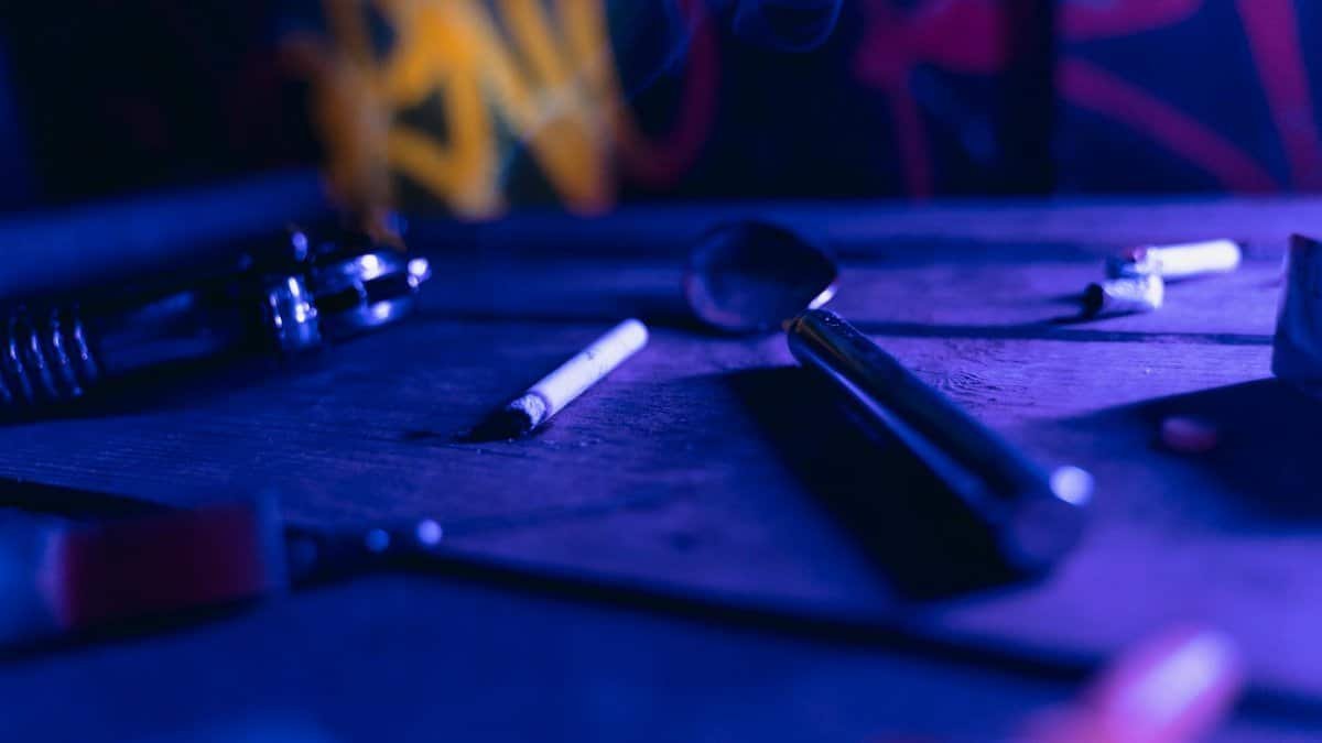Moody scene featuring cigarettes and metallic objects with selective focus, evoking a dramatic ambiance.