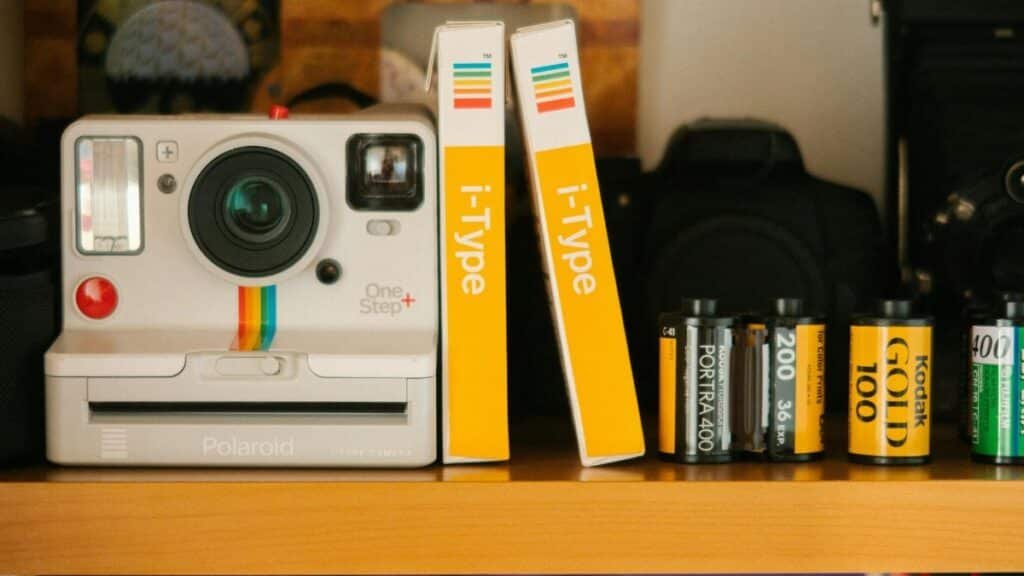 A classic Polaroid OneStep Plus camera with film rolls on a wooden shelf, showcasing retro photography equipment.