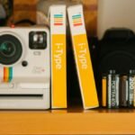 A classic Polaroid OneStep Plus camera with film rolls on a wooden shelf, showcasing retro photography equipment.
