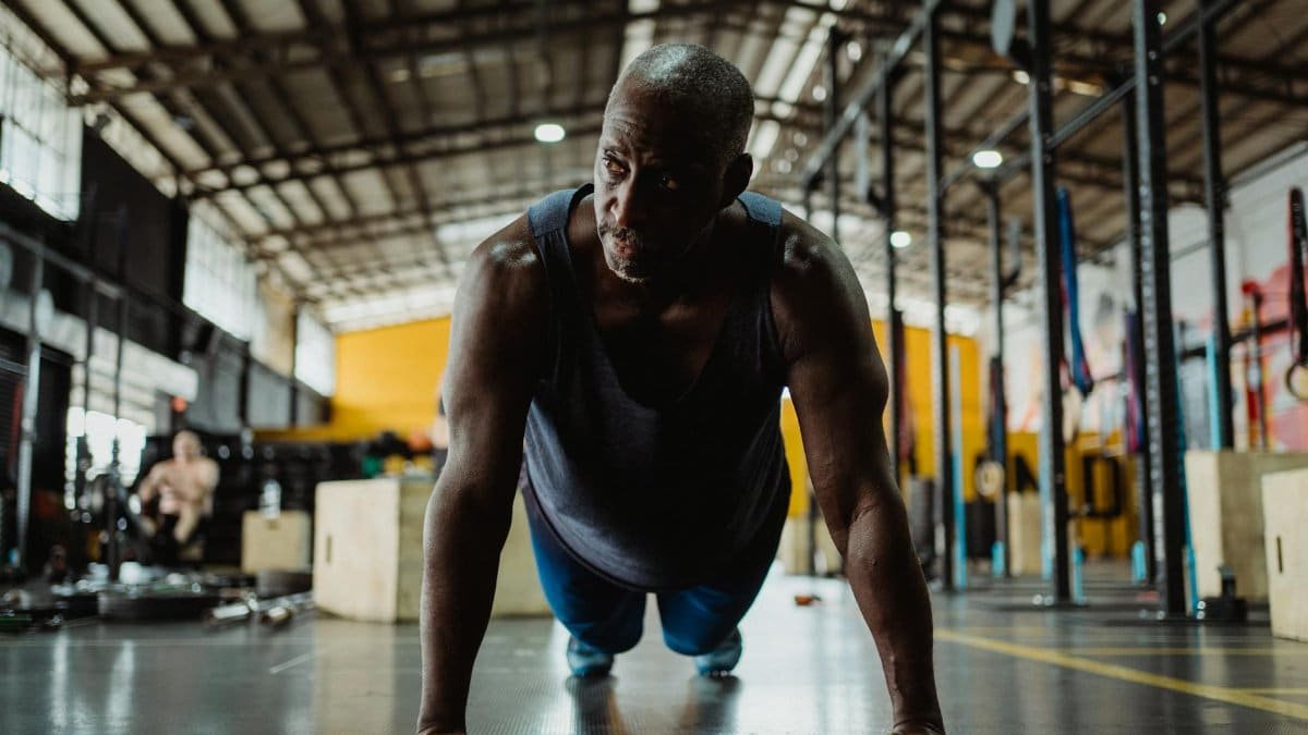 Focused black man performs push-ups in a gym, embodying determination and fitness.