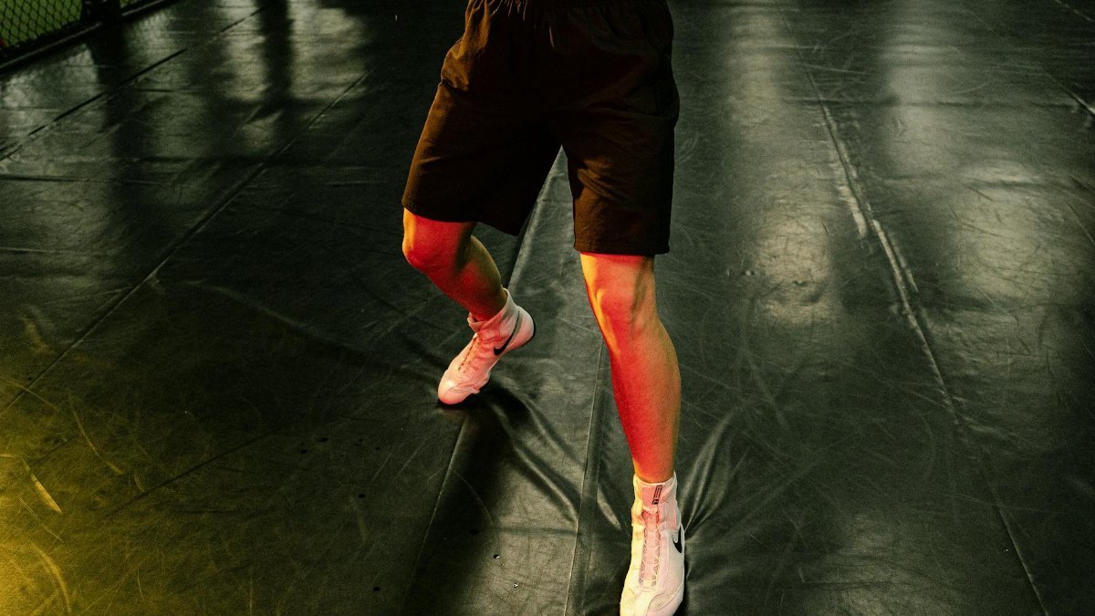 Dynamic action shot of an athlete in black shorts and white sneakers, captured indoors.