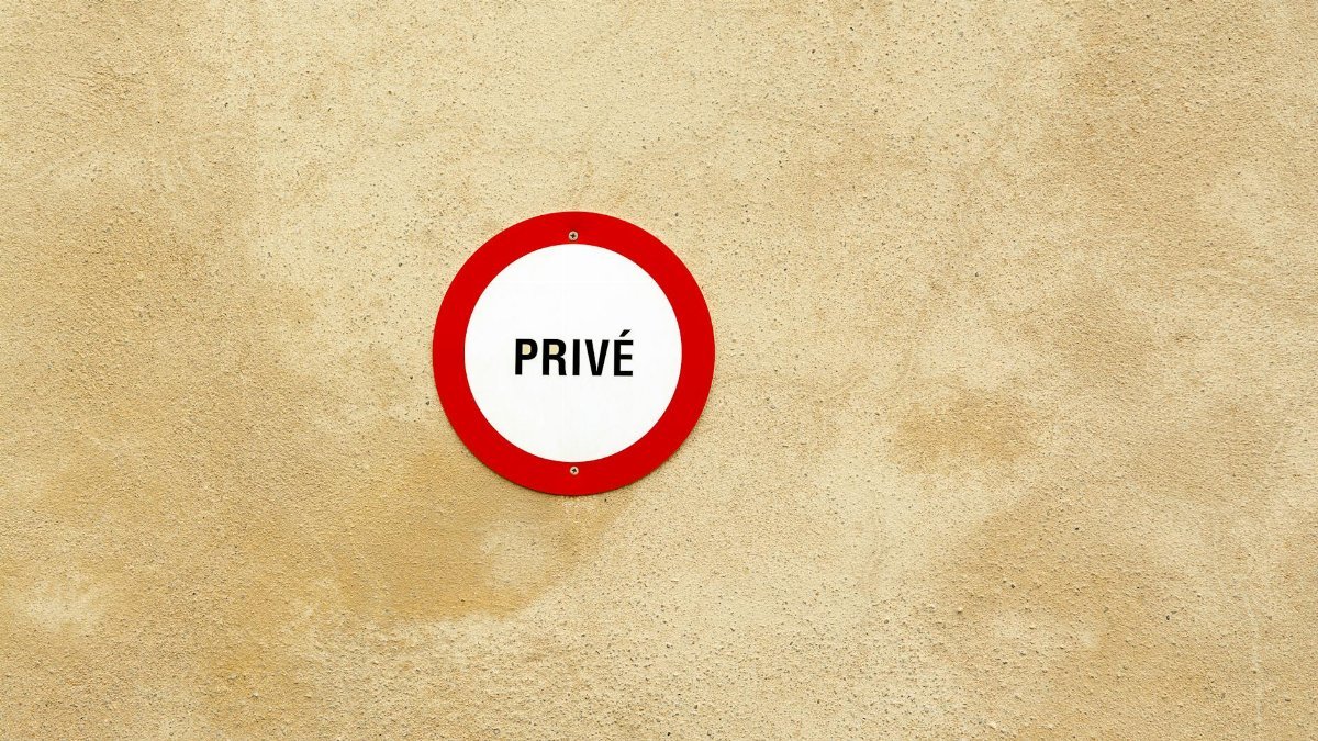 A red and white private sign on a textured beige wall offering ample copy space.