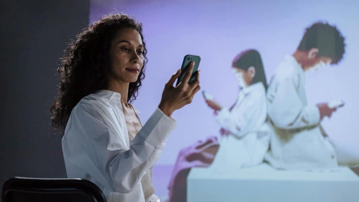 A mother studies her children engrossed in smartphones, highlighting digital safety.