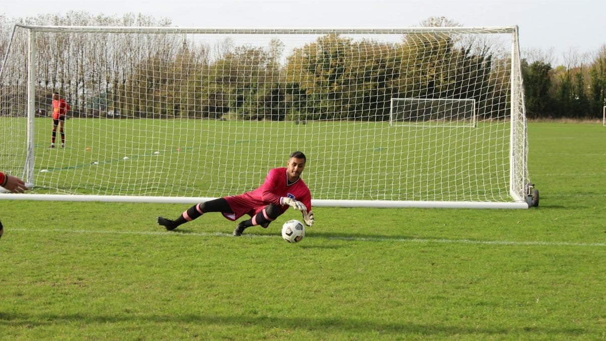 Dynamic scene of a goalkeeper diving to save a goal during a soccer match, showcasing athletic skills.