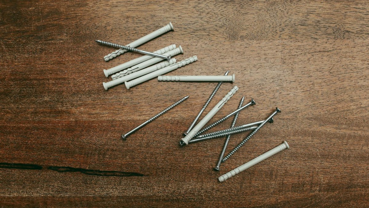 Close-up of screws and nylon anchors laid on a wooden background.